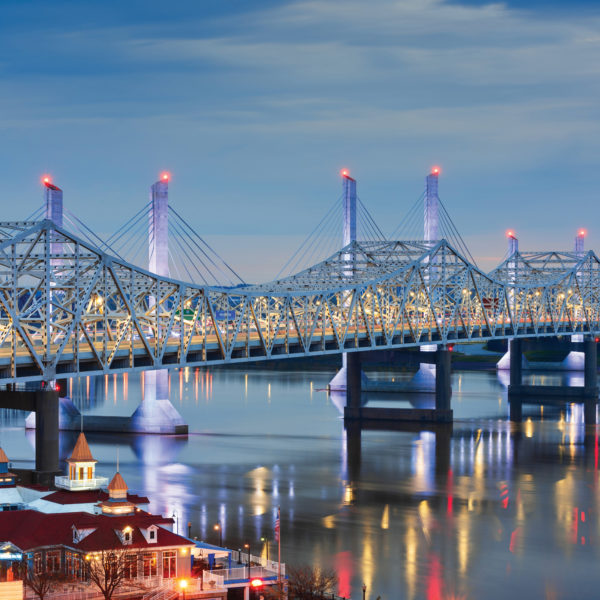 The John F. Kennedy Memorial Bridge, in the foreground, is a six-lane, single deck cantilever bridge that carries southbound Interstate 65 traffic over the Ohio River and into Louisville from Southern Indiana.